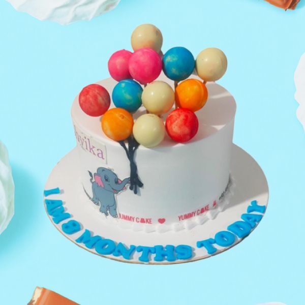 A cake with an elephant and colorful balloons
