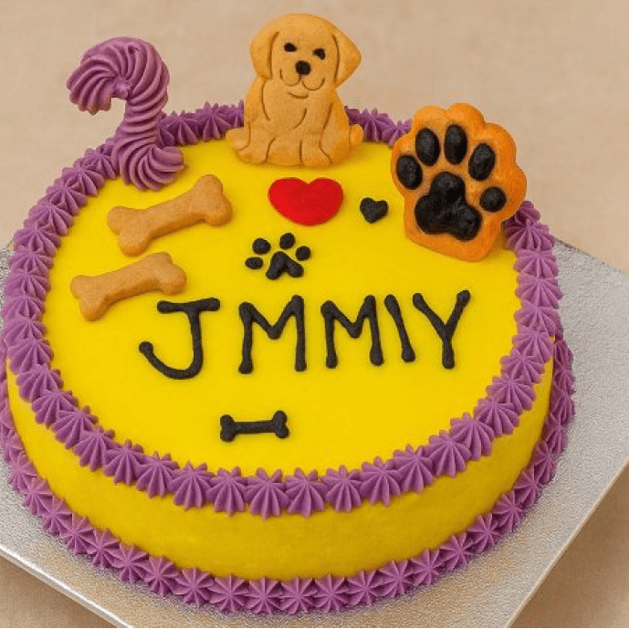 Colorful round dog birthday cake with yellow and purple icing, decorated with dog paw cookie, bones