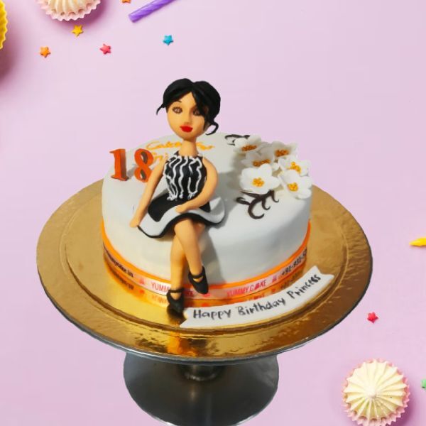 A cake with a figurine of a girl celebrating an 18th birthday