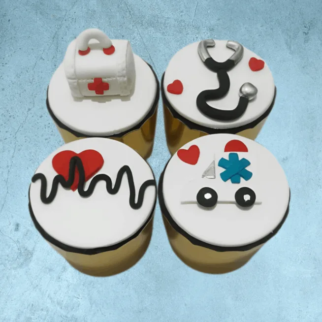 Four cupcakes with medical designs, including a nurse’s uniform, syringe, pills, and stethoscope.