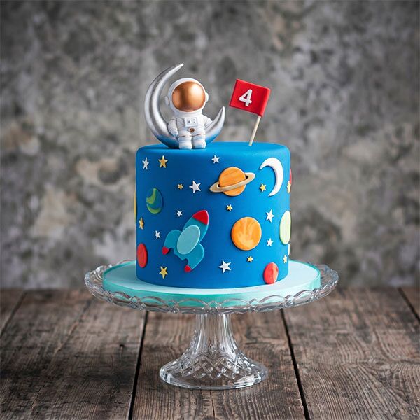 Blue astronaut cake with 3D silver moon topper and red number 4 flag