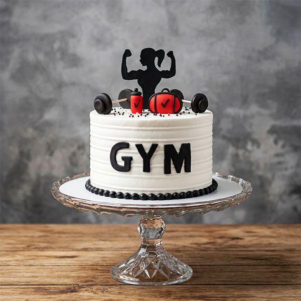 Ribbed white cake with black GYM letters, red gym bag, protein shaker, and female bodybuilder silhouette.