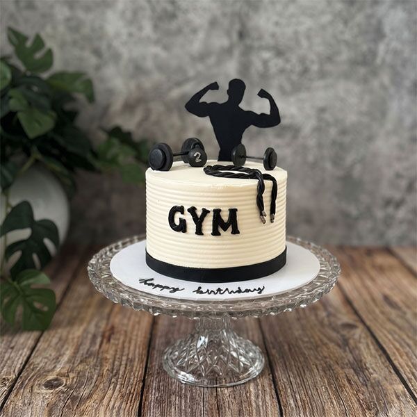 Ribbed white cake with black GYM lettering, jump rope, dumbbells, and bodybuilder silhouette.