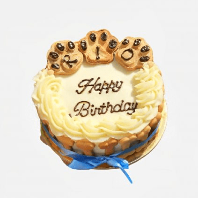 Round dog birthday cake with creamy white frosting, topped with paw cookies