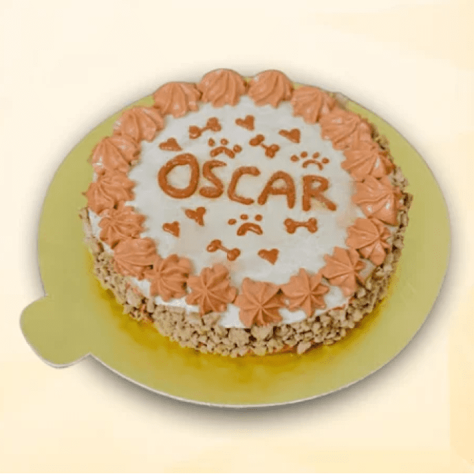 Round dog cake with the name “Oscar” in orange frosting, paw prints, hearts