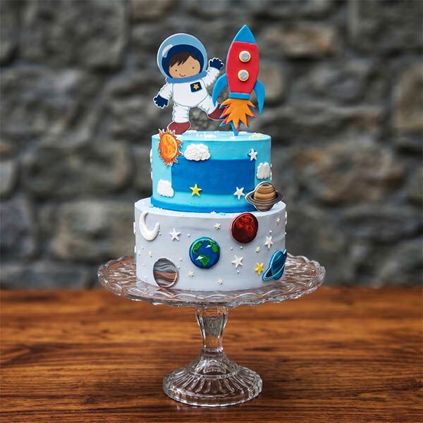 Two-tier blue space cake with cartoon astronaut and rocket toppers.