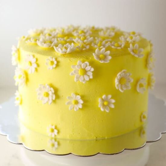 Yellow cake adorned with white daisy flowers