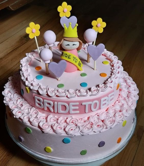 A pink cake with a bride to be on top