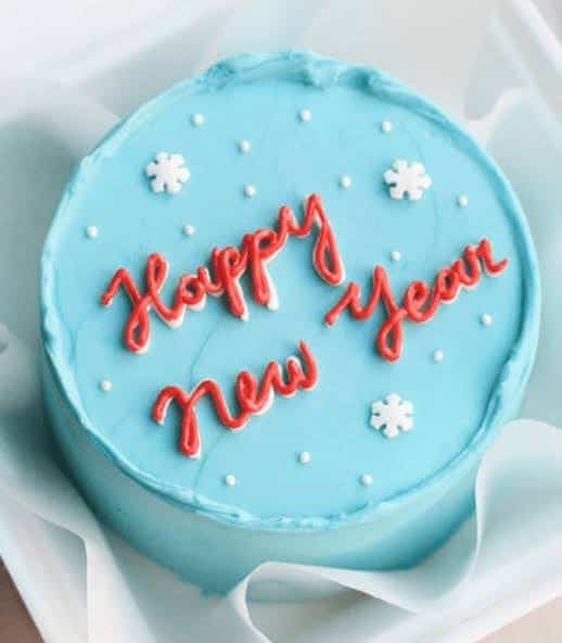 A light blue New Year cake with "Happy New Year" in red icing and snowflake decorations.