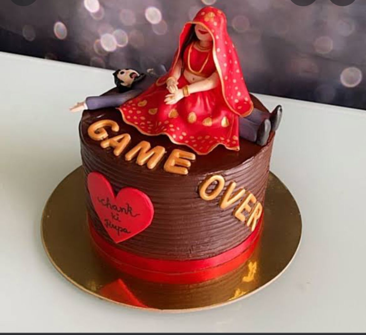 Wedding cake with bride and groom figurine on top. Text on cake reads "Game Over"