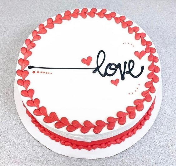 White cake with red heart border and "love" written in the center