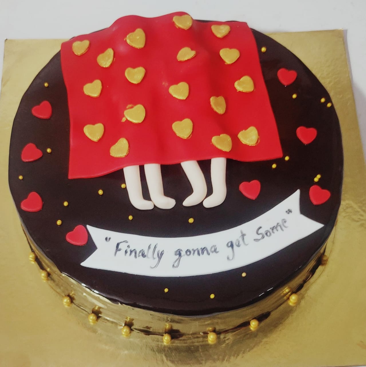 A semi-fondant adult-themed cake with a red skirt design and playful heart decorations.